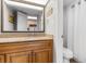 Bathroom with granite countertops, wood cabinets and toilet, reflecting the kitchen in the mirror at 7200 N Ocean Blvd. # 553, Myrtle Beach, SC 29572