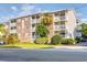 Three-story condo building featuring a brick facade and multiple balconies with white railings and mature landscaping at 1212 Ocean Blvd. S # 202, Surfside Beach, SC 29575