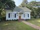 Charming white house with blue shutters, a brick pathway, and mature trees in a tranquil setting at 1403 9Th Ave., Conway, SC 29526