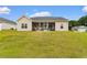 A tan home's backyard featuring a covered patio with outdoor seating and a spacious lawn at 177 Baylee Circle, Galivants Ferry, SC 29544
