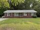 Charming brick home with a well-manicured lawn, gray metal roof, and black shutters at 205 S Oliver Blvd., Hemingway, SC 29554