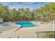 Community pool with large deck area, lounge chairs, and adjacent spa surrounded by trees at 29 Saltwind Loop, Murrells Inlet, SC 29576
