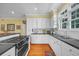 Well-lit kitchen featuring white cabinets, black countertops, stainless steel appliances, and hardwood floors at 3231 Center Rd., Georgetown, SC 29440