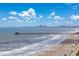 Scenic beach view with pier and cityscape in the distance, perfect for relaxation at 5700 N Ocean Blvd. # Ph12, North Myrtle Beach, SC 29582