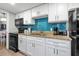 Charming kitchen features black appliances, white cabinets and a striking blue backsplash at 7200 N Ocean Blvd. # 260, Myrtle Beach, SC 29572