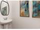 Elegant powder room featuring a pedestal sink, decorative mirror, and modern abstract art at 739 Chazen Way, Longs, SC 29568