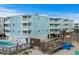 Light blue condo building next to a wooden walkway leading to the beach and outdoor community pool at 824 N Waccamaw Dr. # 203, Murrells Inlet, SC 29576