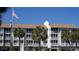 Low-rise condo building with a three-story exterior and a well-maintained facade surrounded by palm trees and the American flag at 9571 Shore Dr. # 318, Myrtle Beach, SC 29572