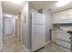 Bright kitchen featuring white appliances and tile flooring, adjacent to a hallway with neutral walls at 1100 Possum Trot Dr. # D106, North Myrtle Beach, SC 29582
