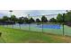 An outdoor tennis court enclosed by a fence, surrounded by greenery and trees at 1100 Possum Trot Dr. # D106, North Myrtle Beach, SC 29582