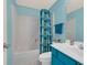 Bathroom with a turquoise vanity and shower with blue and green block patterned curtain at 1221 Tidewater Dr. # 122, North Myrtle Beach, SC 29582