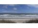 Scenic view of the ocean with gentle waves, soft sand, and blue sky, capturing the essence of coastal serenity at 1221 Tidewater Dr. # 122, North Myrtle Beach, SC 29582