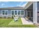 Charming backyard featuring two Adirondack chairs on a lawn, with access to the screened in porch at 1352 Jolly Roger Dr., North Myrtle Beach, SC 29582