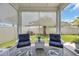 Covered lanai with two chairs, a table, privacy shades, and a view of the manicured backyard at 1352 Jolly Roger Dr., North Myrtle Beach, SC 29582
