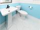 Bathroom featuring a pedestal sink, toilet, white hexagon tile floor and stylish blue wall paneling at 1931 Lakeview Circle, Surfside Beach, SC 29575
