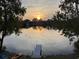 Beautiful sunset view overlooking the lake with a dock and boats, framed by trees, providing a tranquil setting at 1931 Lakeview Circle, Surfside Beach, SC 29575