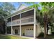 Rear exterior of home featuring a screened porch, lower-level patio, and a garage at 210 Natures View Circle, Pawleys Island, SC 29585