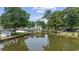 Backyard view featuring a tranquil pond with a charming fence, mature trees, and partial view of the back of the house at 216 Deer Trace Circle, Myrtle Beach, SC 29588