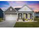 Charming single-story home featuring a manicured lawn, covered porch, and a two-car garage at dusk at 314 Bumble Circle, Murrells Inlet, SC 29576