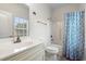Bright bathroom featuring a vanity with a white countertop, a toilet, and a shower with a blue patterned curtain at 4331 Grande Harbour Blvd., Little River, SC 29566