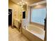 Bright bathroom with a large soaking tub and window, double vanity, decorative lighting, and neutral tile flooring at 4447 River Rd., Little River, SC 29566