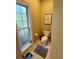 Cozy powder room with a toilet, small window and decor, featuring neutral colors and tile flooring at 4447 River Rd., Little River, SC 29566