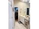 Bathroom with a vanity, decorative lighting, large mirror and neutral tile flooring with the bedroom visible through the doorway at 4447 River Rd., Little River, SC 29566