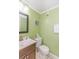 This bathroom features a toilet, a dark wood vanity with sink and mirror, and lime green walls at 4525 S Ocean Blvd. # 406, North Myrtle Beach, SC 29582