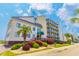 Beautiful view of the exterior of the building from across the street with greenery, palm trees, and blue skies at 4525 S Ocean Blvd. # 406, North Myrtle Beach, SC 29582