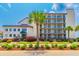 A condo building is landscaped with tropical plants and trees in front of a multi-level building with balconies at 4525 S Ocean Blvd. # 406, North Myrtle Beach, SC 29582
