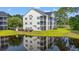 Exterior view of a charming multi-story condo reflecting in a serene pond at 6000 Windsor Green Way # 104, Myrtle Beach, SC 29579
