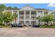 Three-story condo building with white columns and balconies, surrounded by trees and a parking lot at 6000 Windsor Green Way # 104, Myrtle Beach, SC 29579