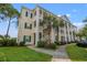 Angle view of the three-story condo building with white columns and balconies, surrounded by trees and grass at 6000 Windsor Green Way # 104, Myrtle Beach, SC 29579