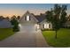 Charming home featuring a two-car garage, manicured lawn, and beautiful landscaping at dusk at 620 Seth Ln., Longs, SC 29568