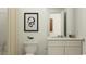 Modern bathroom with a toilet, sleek white vanity, and contemporary black and white art at 6366 Swainson Street Sw, Ocean Isle Beach, NC 28469