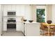 Modern kitchen with white cabinets, stainless steel appliances, and a dining area with seating at 6366 Swainson Street Sw, Ocean Isle Beach, NC 28469