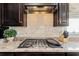 Kitchen featuring a gas stovetop, granite countertops, white backsplash, and dark cabinetry at 6378 Torino Lane, Myrtle Beach, SC 29572