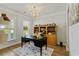 Bright office featuring an elegant black desk, a wooden bookcase, and a decorative chandelier at 6378 Torino Lane, Myrtle Beach, SC 29572