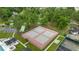 Aerial view featuring well-maintained red and grey tennis courts surrounded by lush greenery at 6681 Wisteria Dr., Myrtle Beach, SC 29588