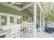 A screened-in porch with white tables and chairs sits beneath a roof, offering a place to relax and enjoy the view at 70 Beachwalker Ct., Georgetown, SC 29440