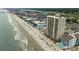Aerial view of condo building on beach with umbrellas, lounge chairs, and neighboring buildings at 912 N Waccamaw Dr. # 904, Garden City Beach, SC 29576