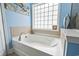 Bathroom with a sleek white bathtub surrounded by tile and a window for plenty of natural light at 106 Cypress Creek Dr., Murrells Inlet, SC 29576