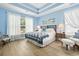 Bright main bedroom with wooden floors and a tray ceiling above a bed with a blue patchwork quilt at 106 Cypress Creek Dr., Murrells Inlet, SC 29576