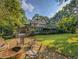Spacious backyard featuring a fire pit area, deck, lush lawn, and beautiful landscaping at 1073 Crooked Oak Dr., Pawleys Island, SC 29585