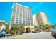 Exterior view of a high-rise condo complex featuring balconies and palm trees in front of the entrance at 1207 S Ocean Blvd. # 51012, Myrtle Beach, SC 29577