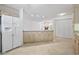 Open kitchen layout with granite countertops, wooden cabinetry, white refrigerator and access to another living area at 1468 Fox Hollow Way, North Myrtle Beach, SC 29582
