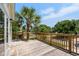 Expansive wooden deck overlooking a serene street, framed by a lush palm tree and a clear blue sky at 154 Cedar Point Ave., Murrells Inlet, SC 29576