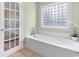 Relaxing bathroom with a soaking tub and a window for natural light, complemented by a tiled floor at 213 South Myrtle Dr., Surfside Beach, SC 29575