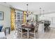 Charming dining area connected to the kitchen, featuring a round table, elegant chandelier, and bright floral curtains at 213 South Myrtle Dr., Surfside Beach, SC 29575