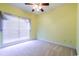 Bedroom with ceiling fan, neutral carpet, pale yellow walls, and large window with natural light at 2499 Burning Tree Ln., Little River, SC 29566